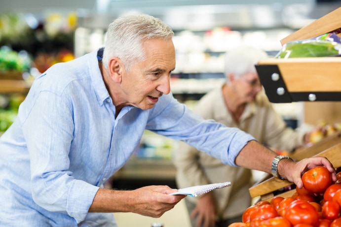 Homme agé qui regarde des tomates